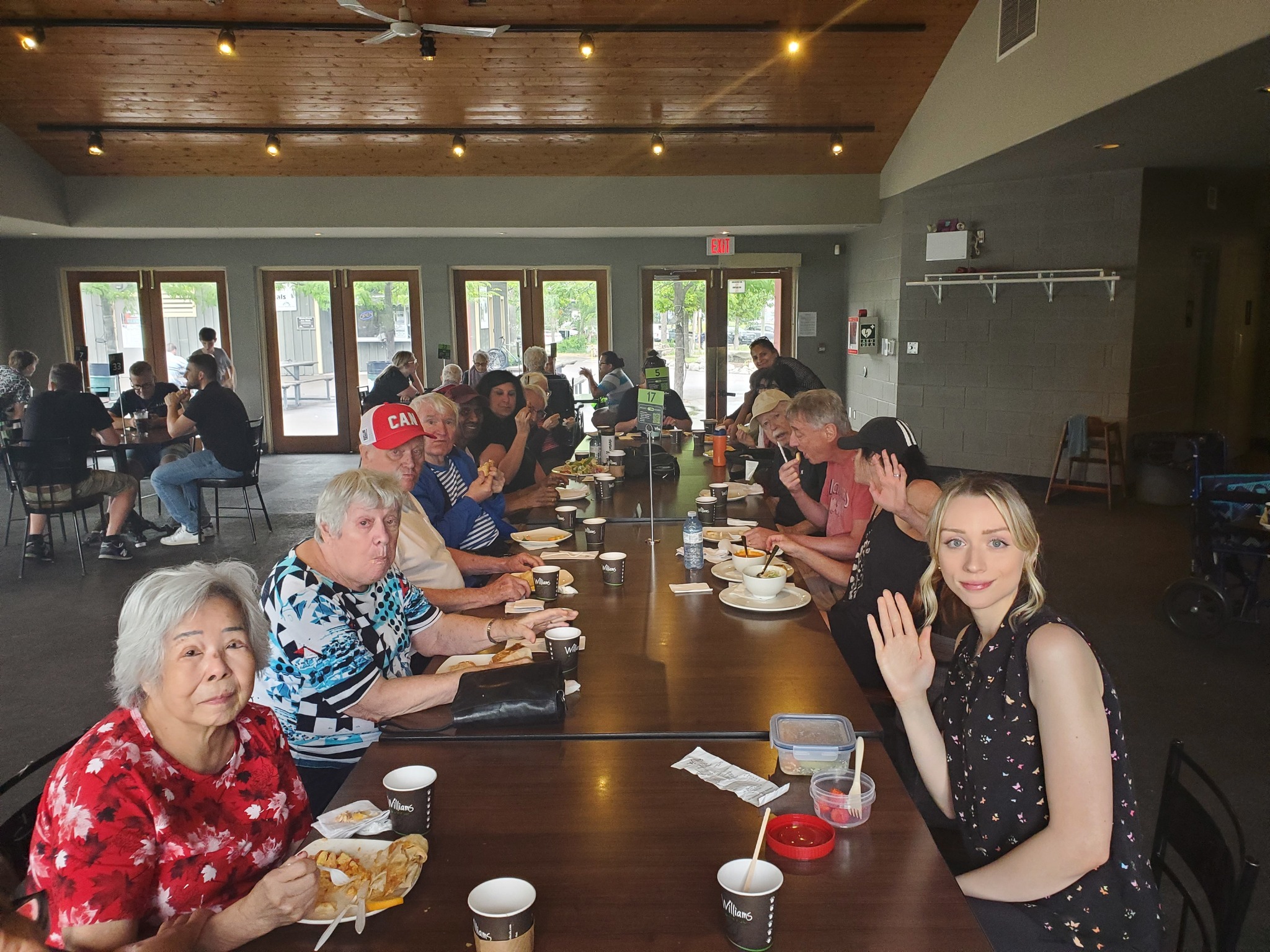 Group of adults seated together at a long dining table enjoying a meal during a community gathering.
